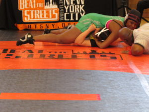 Senior Shaniece Hunter grins as she nearly pins her opponent at a recent Beat the Streets wrestling event.