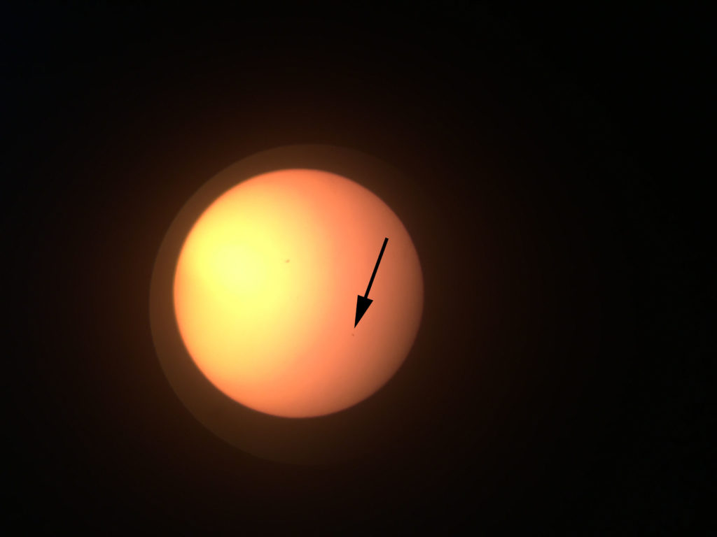The arrow points to the small round speck. That is actually the planet Mercury as it is crossing between the Earth and the Sun.