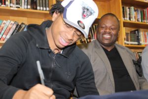 Jefferson cracks a smile while signing his commitment letter as his father, Wayne, looks on. (Photo by Abel Alexander)